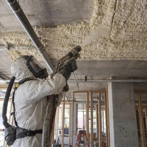 Installer applying thermal acoustic spray under a concrete deck