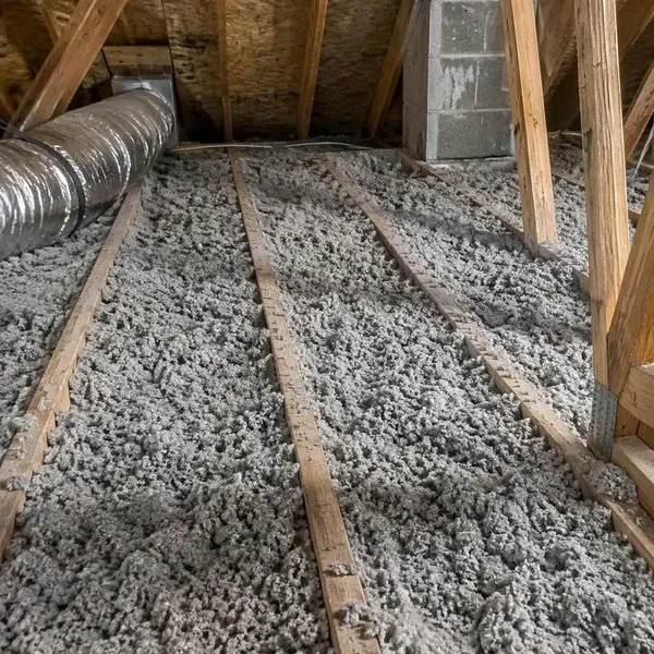 Grey cellulose insulation filling attic floor joist cavities