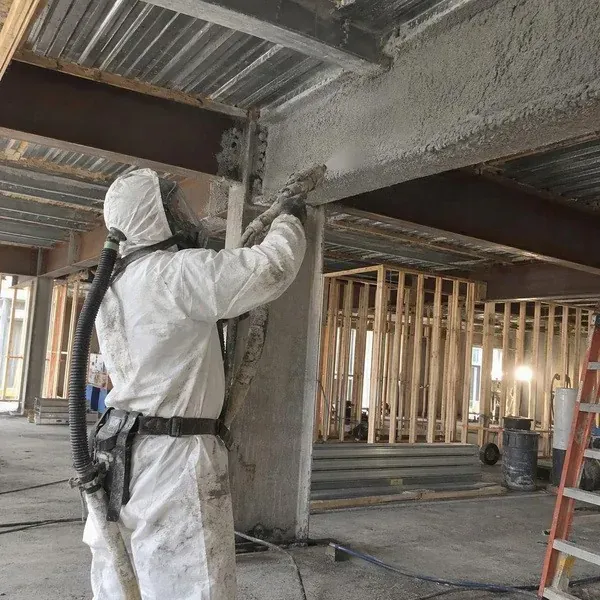 Installer applying spray fireproofing to a structural steel beam