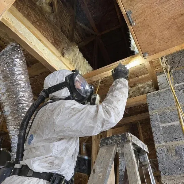 Energy auditor checking an attic access hatch for air leaks