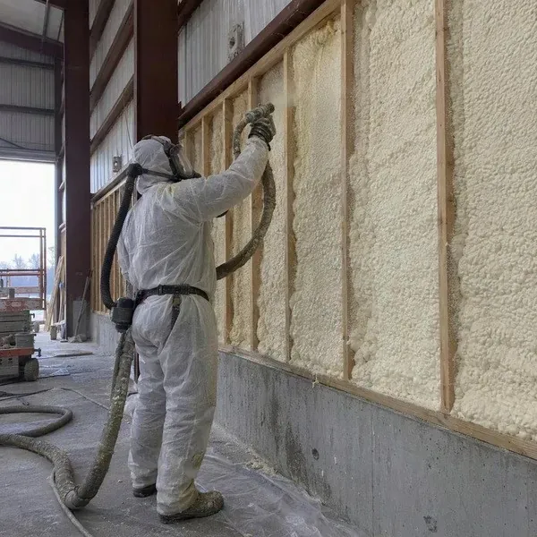 Installer spraying foam on a tall industrial building wall