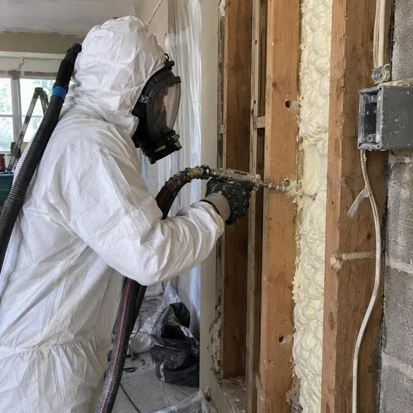 Technician injecting foam into a closed wall cavity