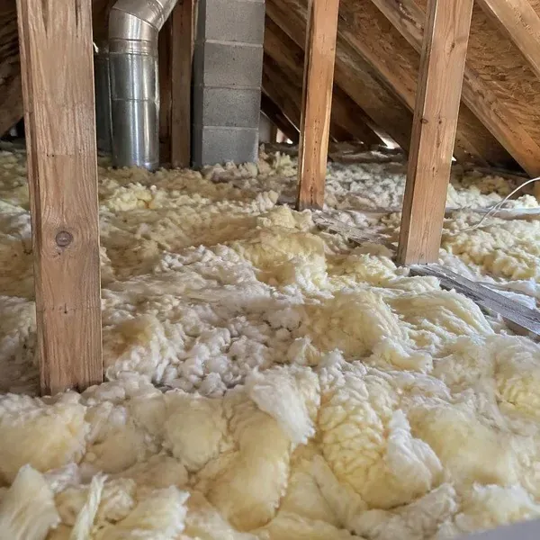 Old loose fiberglass insulation covering an attic floor