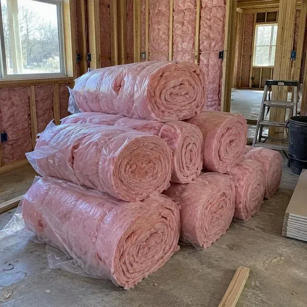 Pink fiberglass insulation rolls stacked in an unfinished room
