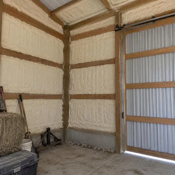Pole barn walls insulated with spray foam beside a sliding door