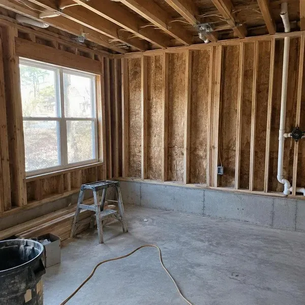 Stripped renovation room with open stud walls before spray foam