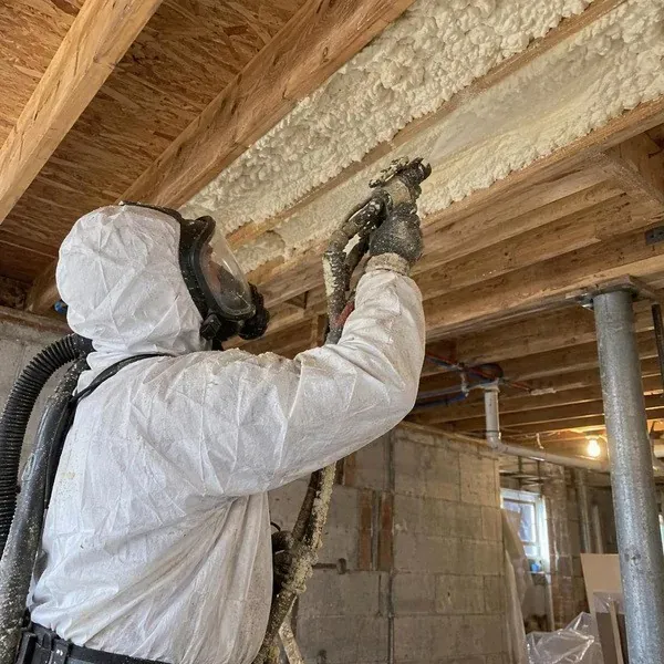 Installer spraying foam under an upstairs subfloor